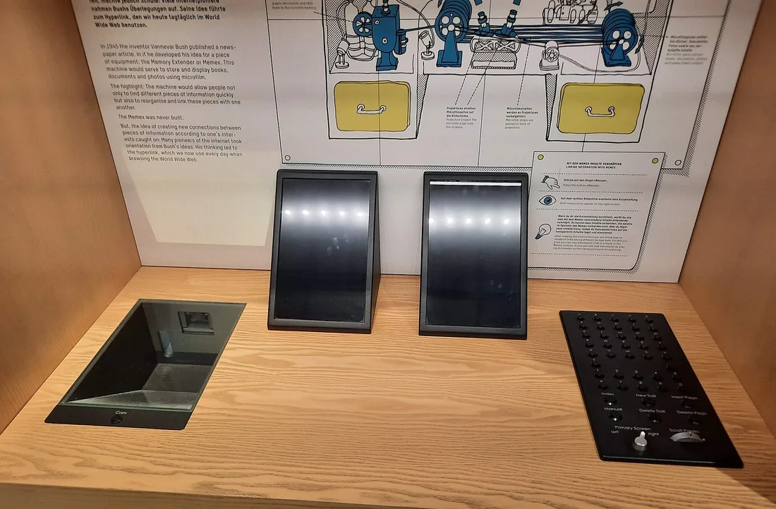 Une reconstitution du memex exposée dans un musée : un bureau en bois portant deux écrans inclinés, un clavier à droite et un lecteur encastré à gauche, devant un panneau explicatif.