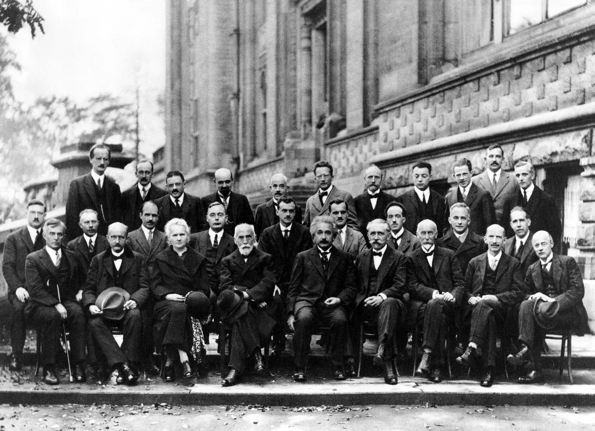 The group photo of the 1927 Solvay Conference: twenty-nine scientists in suits across three rows, including Marie Curie and Albert Einstein in the front row.